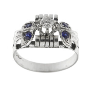 Anello stile Art déco in oro bianco 18kt con diamante taglio brillante da 0.18 ct - colore FG e purezza VS e 4 zaffiri da 0.08 ct cad., totale 0.32 ct.